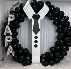 black and white balloons are arranged around a man's tie in the shape of a wreath