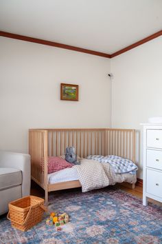 a small child's bed in a room with white furniture and blue rugs