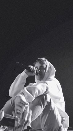 a man sitting on top of a chair while holding a microphone in his right hand