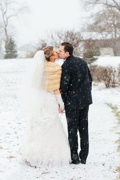 a bride and groom kissing in the snow