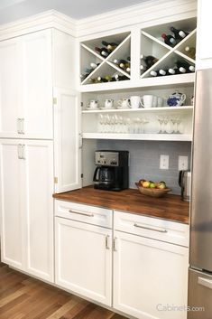 a kitchen with white cabinets and wooden counter tops