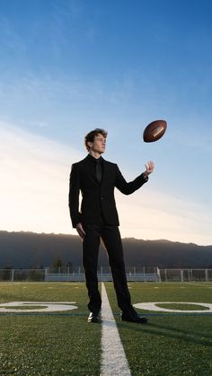 a young man in a suit is throwing a football on the field at sunset or dawn