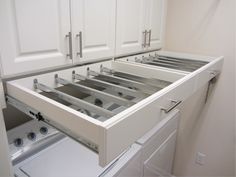 a kitchen with white cabinets and an open drawer