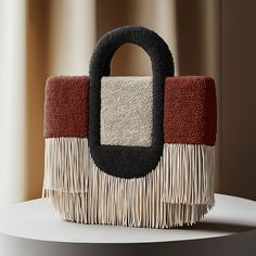 a handbag with fringes on it sitting on top of a white table next to a window