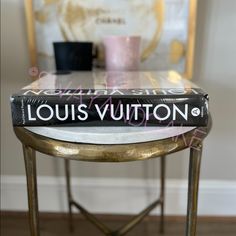 the book louis vuitton is sitting on top of a small table in front of a chair