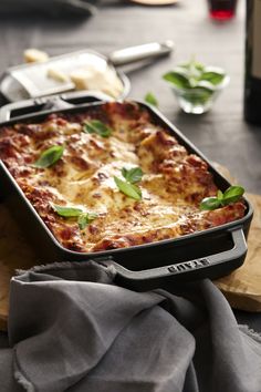 a casserole dish is sitting on a cutting board with napkins and utensils