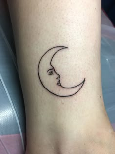 a woman's foot with a small crescent moon tattoo on the side of her leg