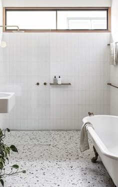 a white bath tub sitting under a window next to a sink