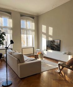 a living room with hard wood floors and large windows