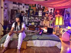 a woman sitting on top of a bed in a room filled with pictures and lights