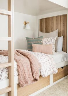 a bed with pillows and blankets on top of it next to a wooden headboard