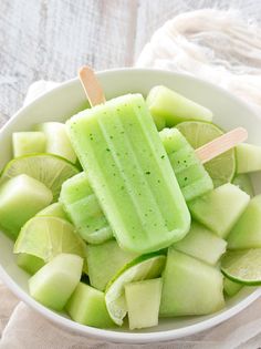 a white bowl filled with green popsicles and lime slices