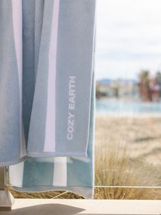 a towel hanging on a window sill in front of a beach and grass area