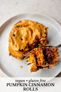 a white plate topped with a piece of pumpkin cinnamon roll next to a bite taken out of it