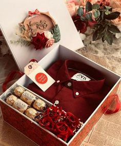 a red shirt and some wine bottles in a box with flowers on the table next to it