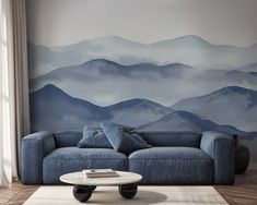 a living room with a blue couch and mountains painted on the wall