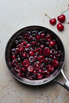 a pan filled with cherries on top of a table