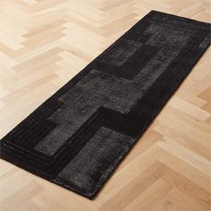 a black rug is on the floor with wooden floors and parquets in the background