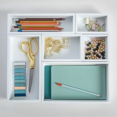 an assortment of office supplies including pencils, markers, and other items on a white shelf