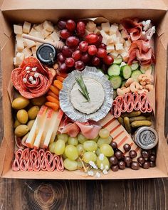 a cardboard box filled with different types of food and snacks on top of a wooden table