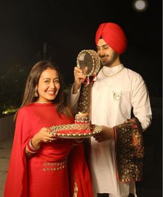 a man and woman holding a cake with a mirror in front of them on top of a table