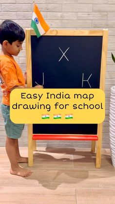 a young boy standing in front of a blackboard with an easy india map drawn on it