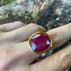 a person's hand with a ring on it and a red stone in the middle