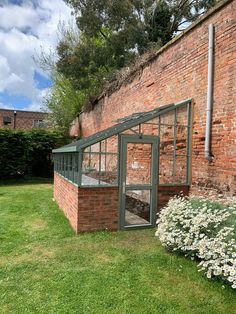 an old brick building with a small green house in the middle of it's yard