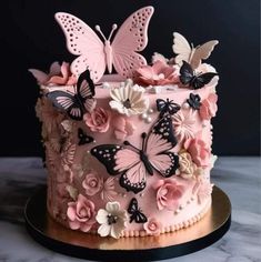 a pink cake decorated with butterflies and flowers