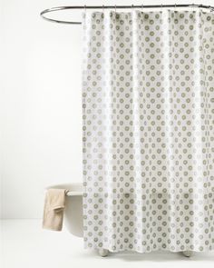 a shower curtain with white and green polka dots on it, next to a toilet