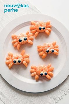 four orange candies with googly eyes on a white plate, one is made to look like a cat