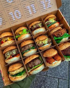 a box filled with lots of hamburgers sitting on top of a brick floor next to a person