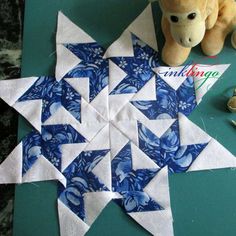 a teddy bear sitting next to a blue and white quilted star ornament