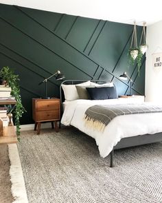 a bedroom with dark green walls and white bedding