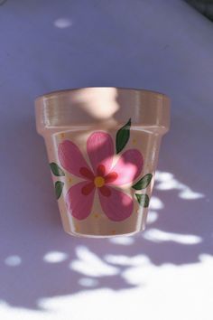 a pink flower pot sitting on top of a white table next to a shadow from the sun