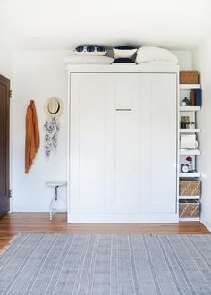 a bedroom with white walls and wooden flooring has a blue rug on the floor