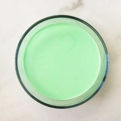 a glass filled with green liquid sitting on top of a white counter