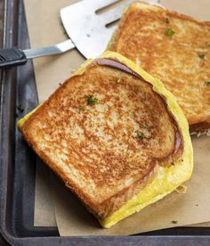 two toasted sandwiches sitting on top of a pan with utensils next to them