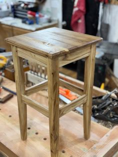 a small wooden stool sitting on top of a table in a room filled with tools