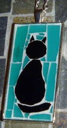 a black cat sitting on top of a blue and white tile floor next to a chain