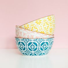 three colorful bowls sitting on top of a white table next to a pink and blue wall