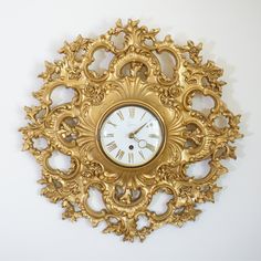 an ornate gold clock is hanging on the wall