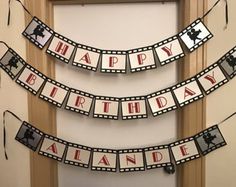 a happy birthday banner is hanging on the wall in front of a window with film strips