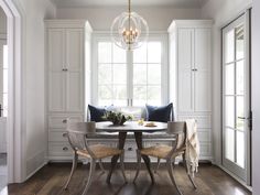 a dining room table with two chairs and a chandelier hanging from the ceiling