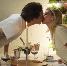 a man and woman kissing in front of a table