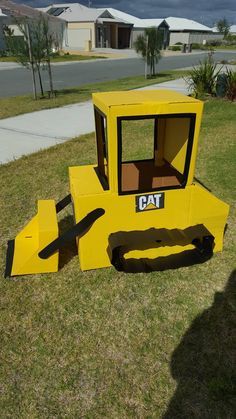 a construction vehicle made out of cardboard sitting in the grass