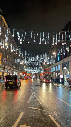 a city street filled with traffic and covered in christmas lights