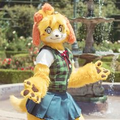 a stuffed animal dressed in a dress standing next to a fountain with its arms spread out