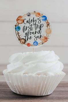 a cupcake sitting on top of a wooden table next to a sign that says cake's first trip around the sun