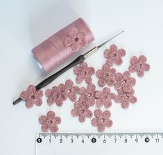 pink crochet flowers next to a needle and measuring tape